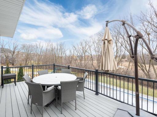 Enjoy outdoor living at its finest on the maintenance-free deck, offering expansive views of the pool, patio, and private backyard. The space is perfectly situated with a serene backdrop provided by a natural tree line.