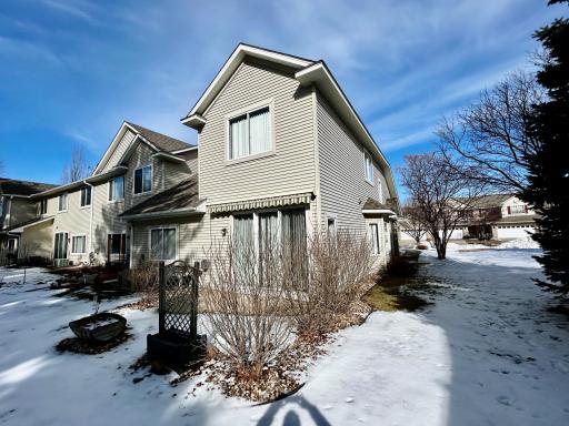 View of the back of the home. There is a very private patio with shrubs and the owner left gardening containers for above ground plantings.