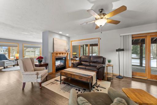 Step into the open and inviting hearth room with fireplace, where new wood flooring creates a warm, cohesive flow throughout the primary living areas. The spacious living room is highlighted by a ceiling fan and a striking two-sided gas fireplace.
