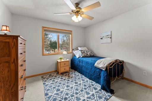 Two additional bedrooms offer serene views of the yard, cozy carpeting, and ceiling fans for added comfort.