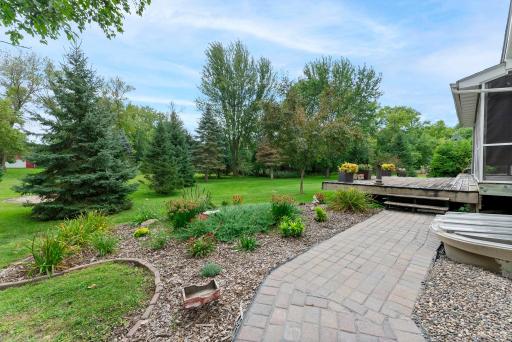 The expansive yard showcases mature trees, a flower garden and beautiful landscaping.