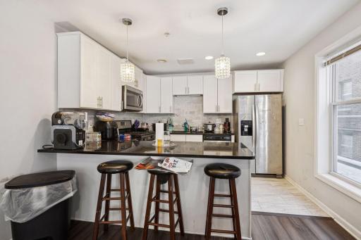 Unit 1 kitchen with warm sconces, natural light and stainless steel appliances.