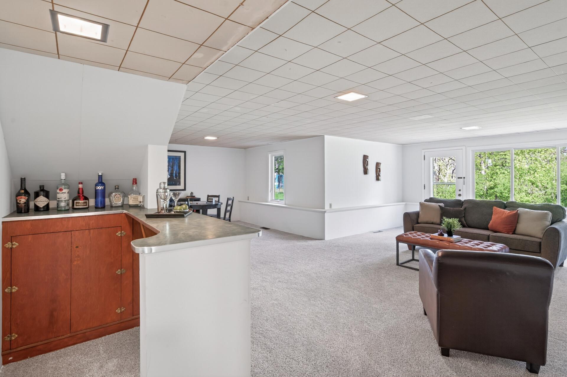 Lower level has a bar under the stairs and a game area. Door opens to the maintenance free deck and back yard