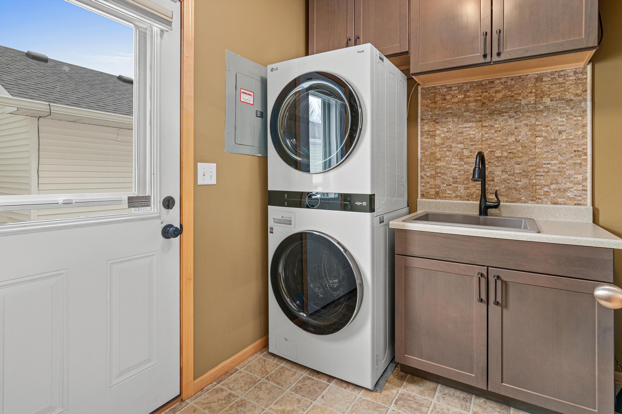 This laundry room and back entry is an absolute delight! In the fall of 2022 new storage cabinetry, sink, faucet , backsplash, and stackable washer and dryer were added to make the laundry room both more stylish and functional.