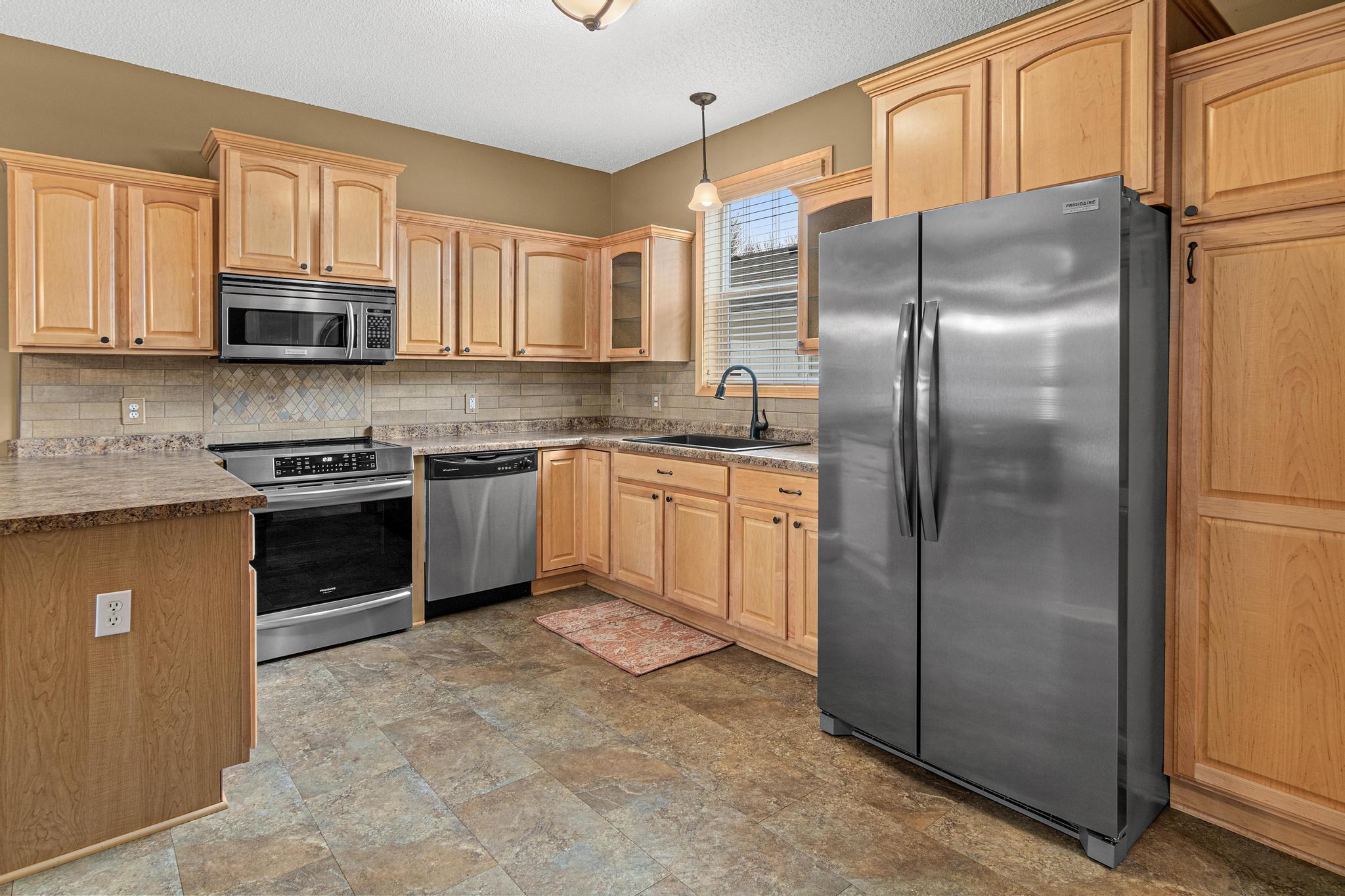 This tasteful kitchen has timeless appeal. The owner made several updates in recent years including replacing the floor, the fridge and range, adding glass fronts to the cabinets that flank the sink and rollouts to all of the lower cabinets!