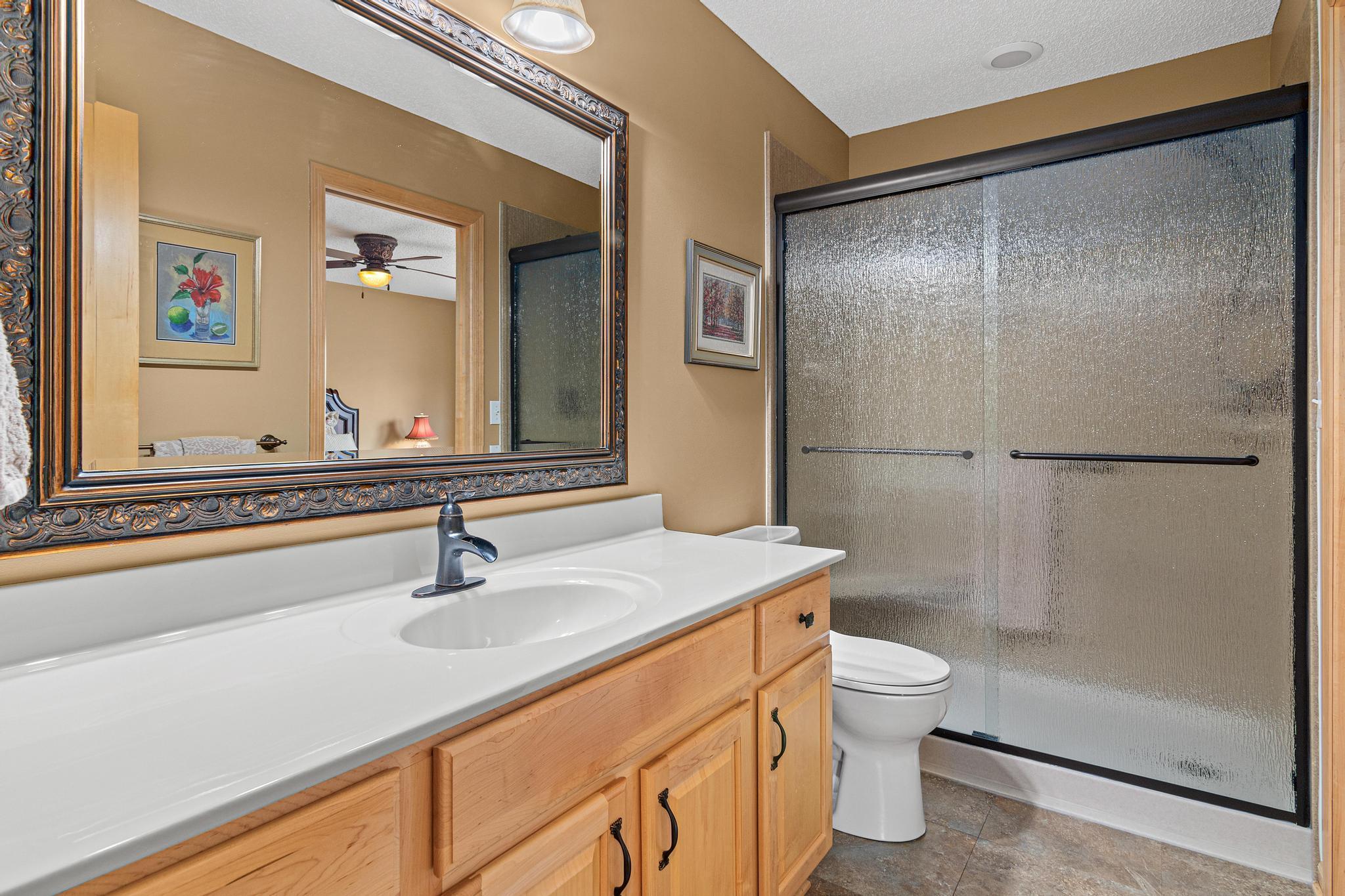 The upper level bathroom has a pocket door to the bedroom as well as access from the hall. This bathroom has newer flooring, hardware, lighting, faucet, and a nearly brand new walk-in shower with niches for hair products as well as a small seat.