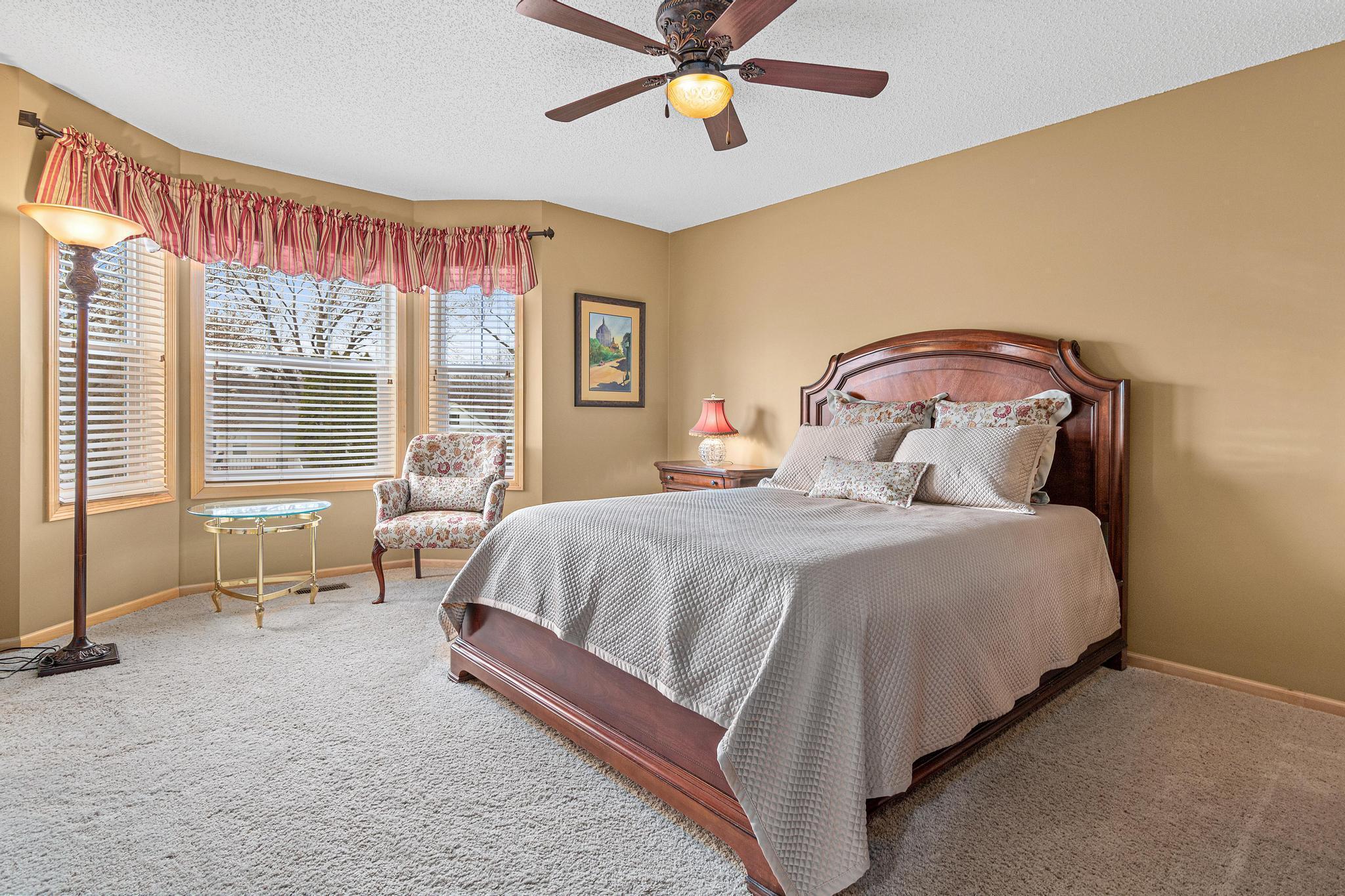 The primary bedroom is large and serene. The large bay windows have a lovely western view. The fan has a dimmable light and remote control so you can make the needed changes without leaving your bed!