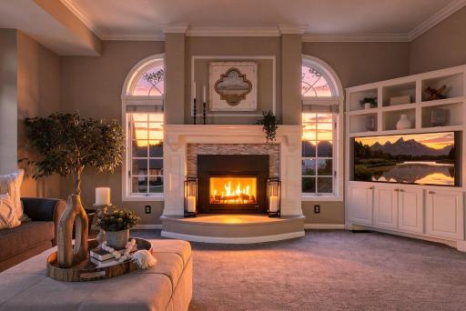 As evening falls, the family room's fireplace glows warmly beneath arched glass-topped windows, creating a rich, welcoming ambiance for cozy nights in.