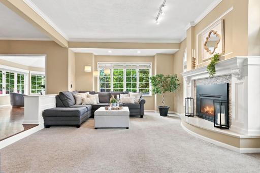 The living room offers a spacious, light-filled layout with a cozy sectional, gas fireplace, and large picture window framing the backyard's greenery.