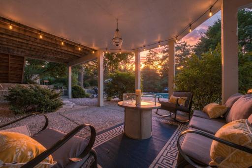 As twilight settles over the covered patio, string lights and glowing fire tables set the mood for the evenings well spent with the pool glimmering just beyond the seating area.