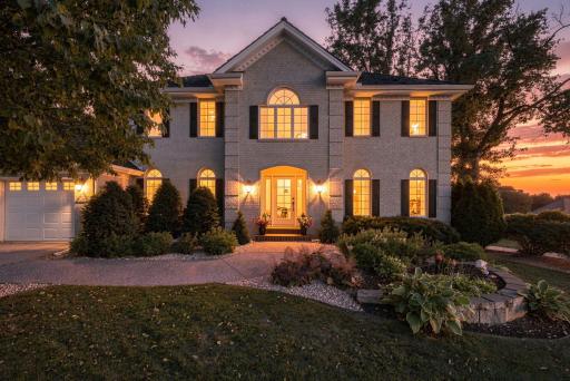 As dusk settles in, the homes' warmly lit windows and grand front entrance create an inviting welcome, a stunning nighttime introduction to this Olympia Hills estate.