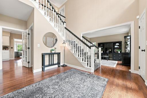 This beautiful staircase and foyer offer a graceful curved railing, hardwood floors, and an inviting entry vignette.