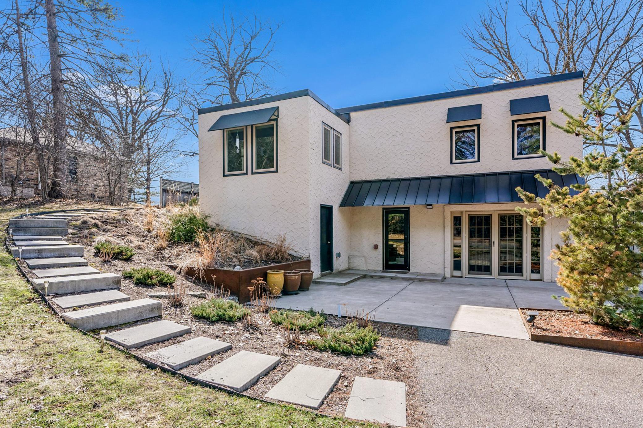 Beautiful curb appeal with brand new Dura-Last roof in 2024, newer windows, new layer of stucco and paint, black metal awnings, concrete paver steps, and professional landscaping.