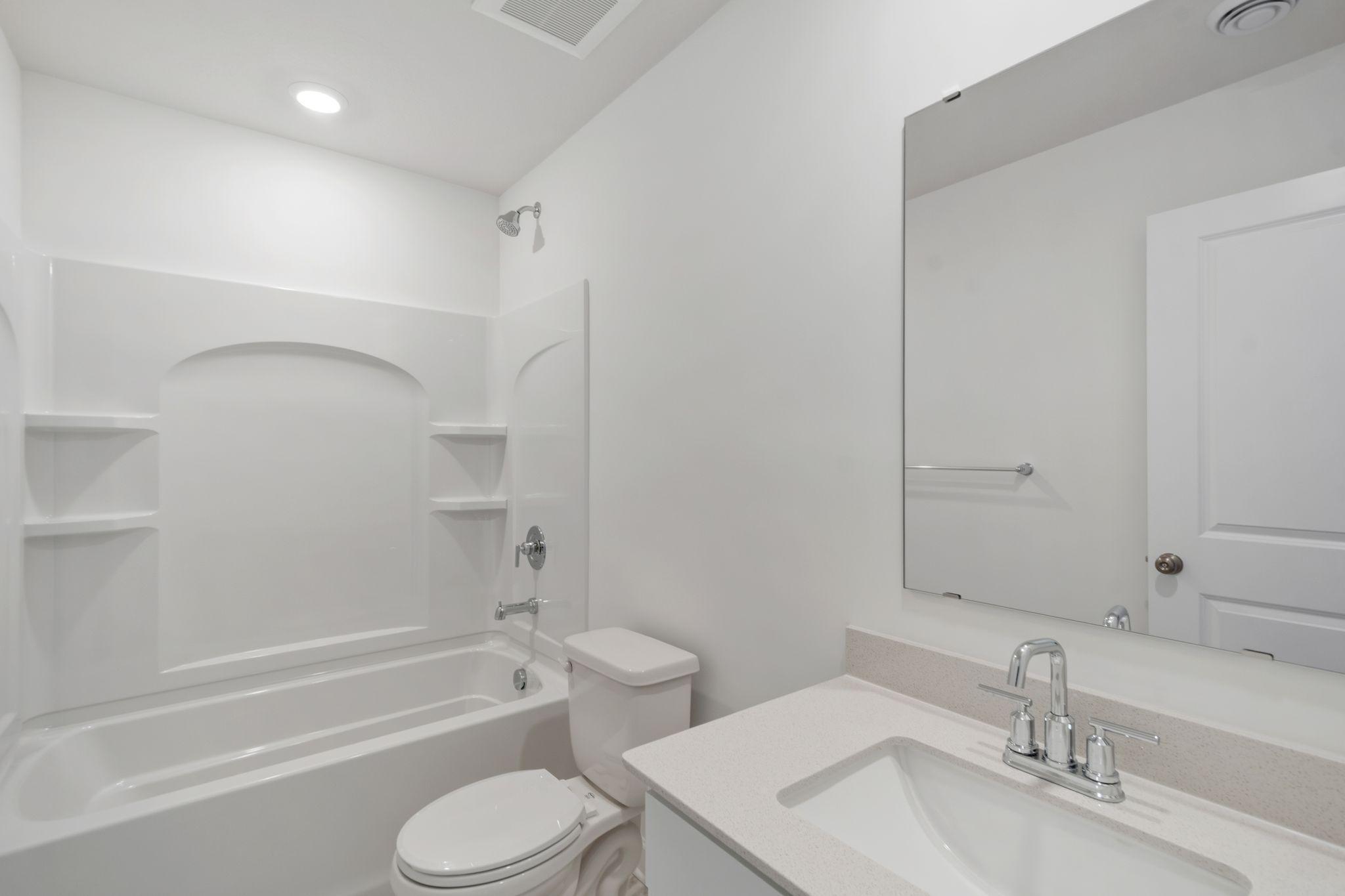 This full bathroom is located near the main level secondary bedrooms for convenient access, featuring a sink and shower-tub combination.