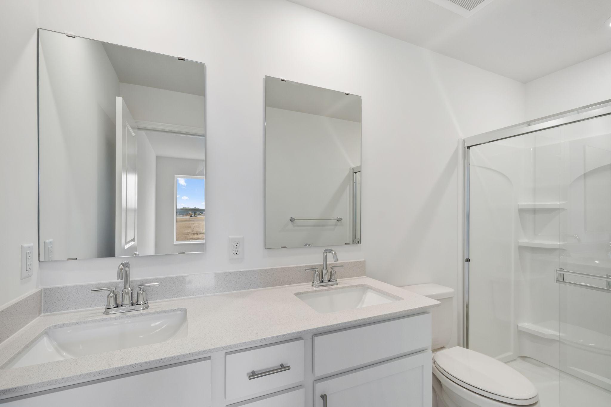 The private bathroom includes a stylish vanity and a glass-enclosed shower for a spa-like atmosphere