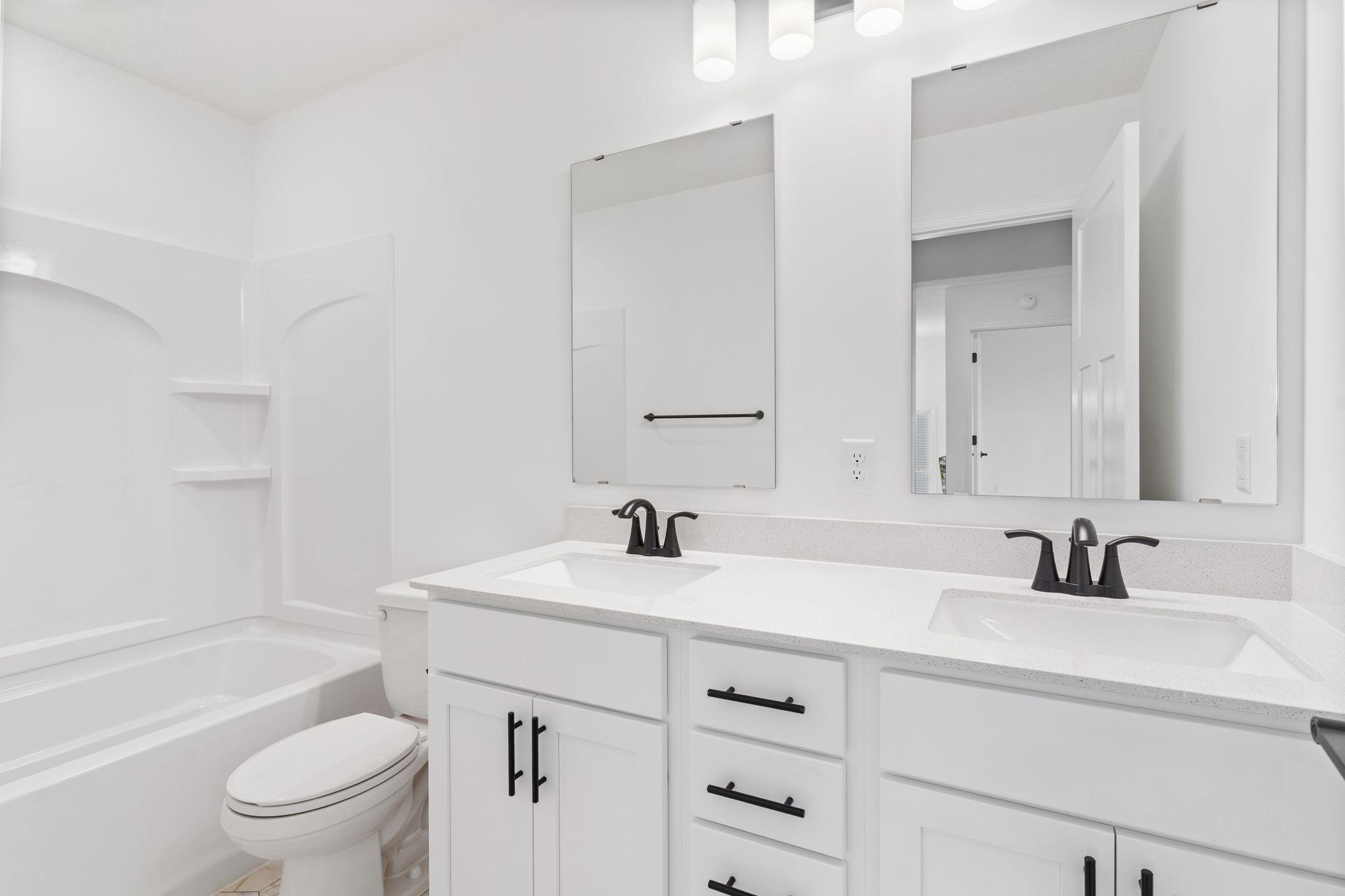 This shared full bathroom features dual sinks and a shower-tub combination.