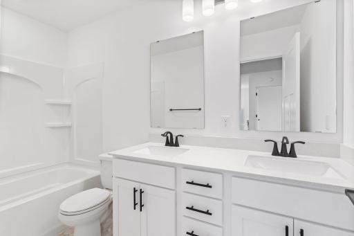 This shared full bathroom features dual sinks and a shower-tub combination.