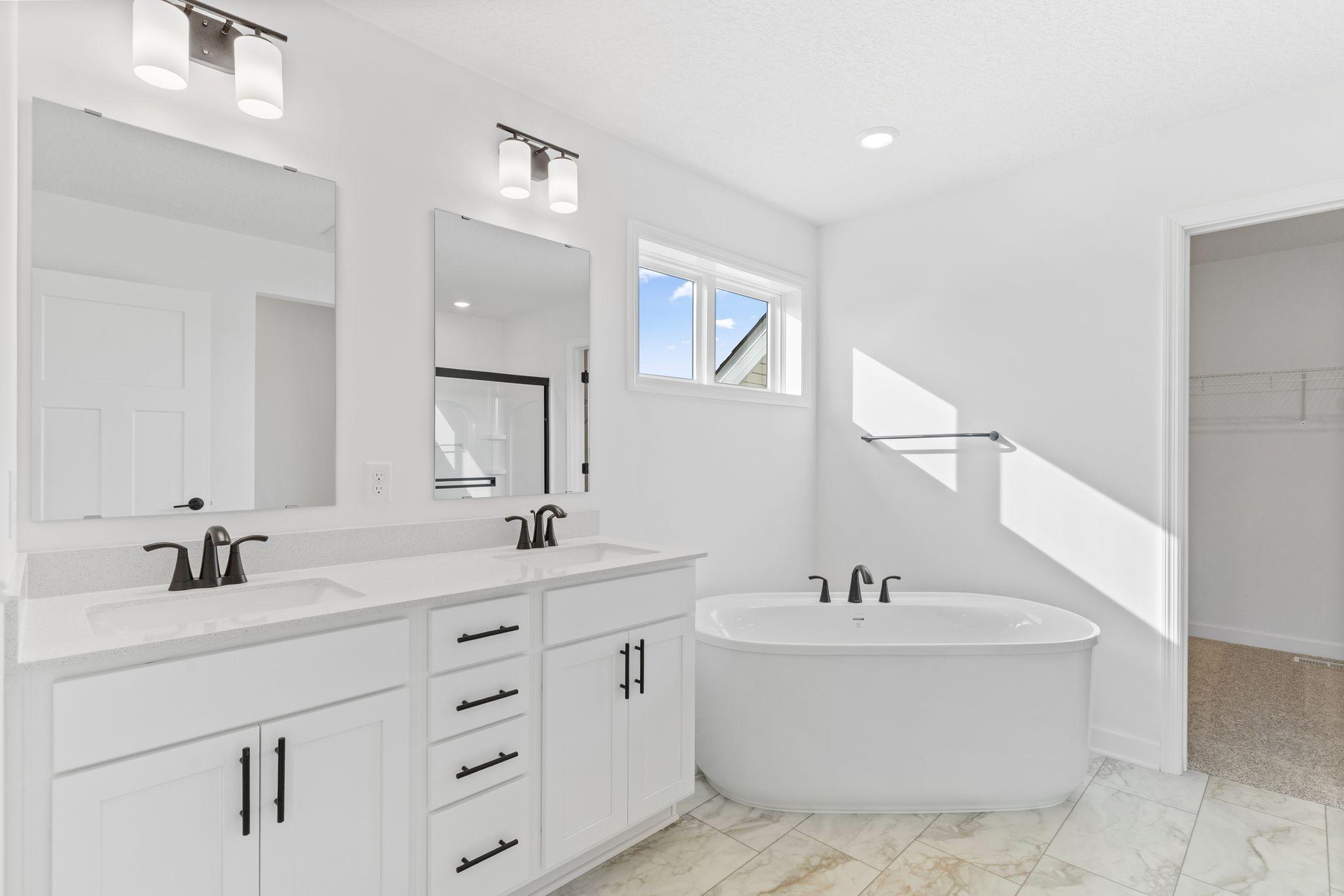 Dual sinks, a glass-enclosed shower and a separate soaking tub contribute to the spa-like atmosphere of the en-suite bathroom