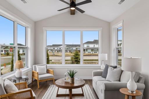 Bright sunroom filled with natural light, featuring three walls of expansive windows for warmth and views