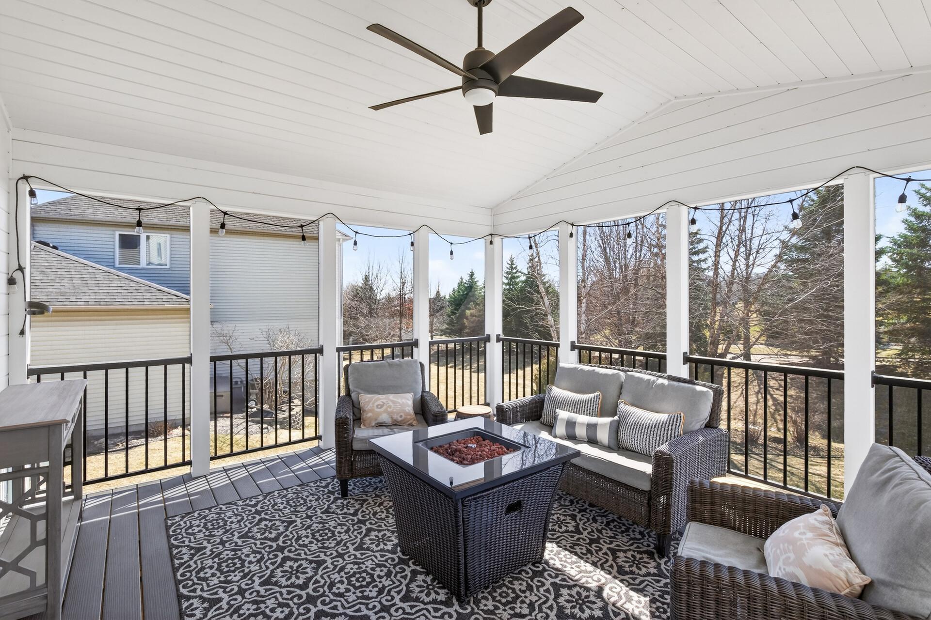 Relax in the screen porch featuring a vaulted ceiling and wood paneling overlooking a private, tree-lined yard.