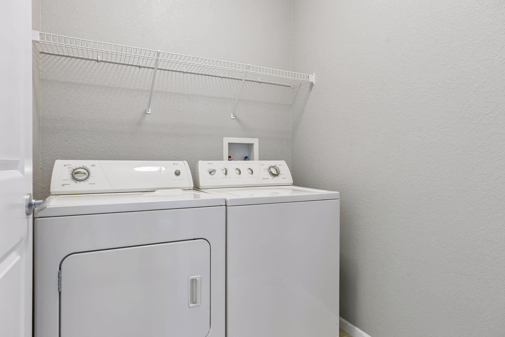 In-unit laundry with shelving.