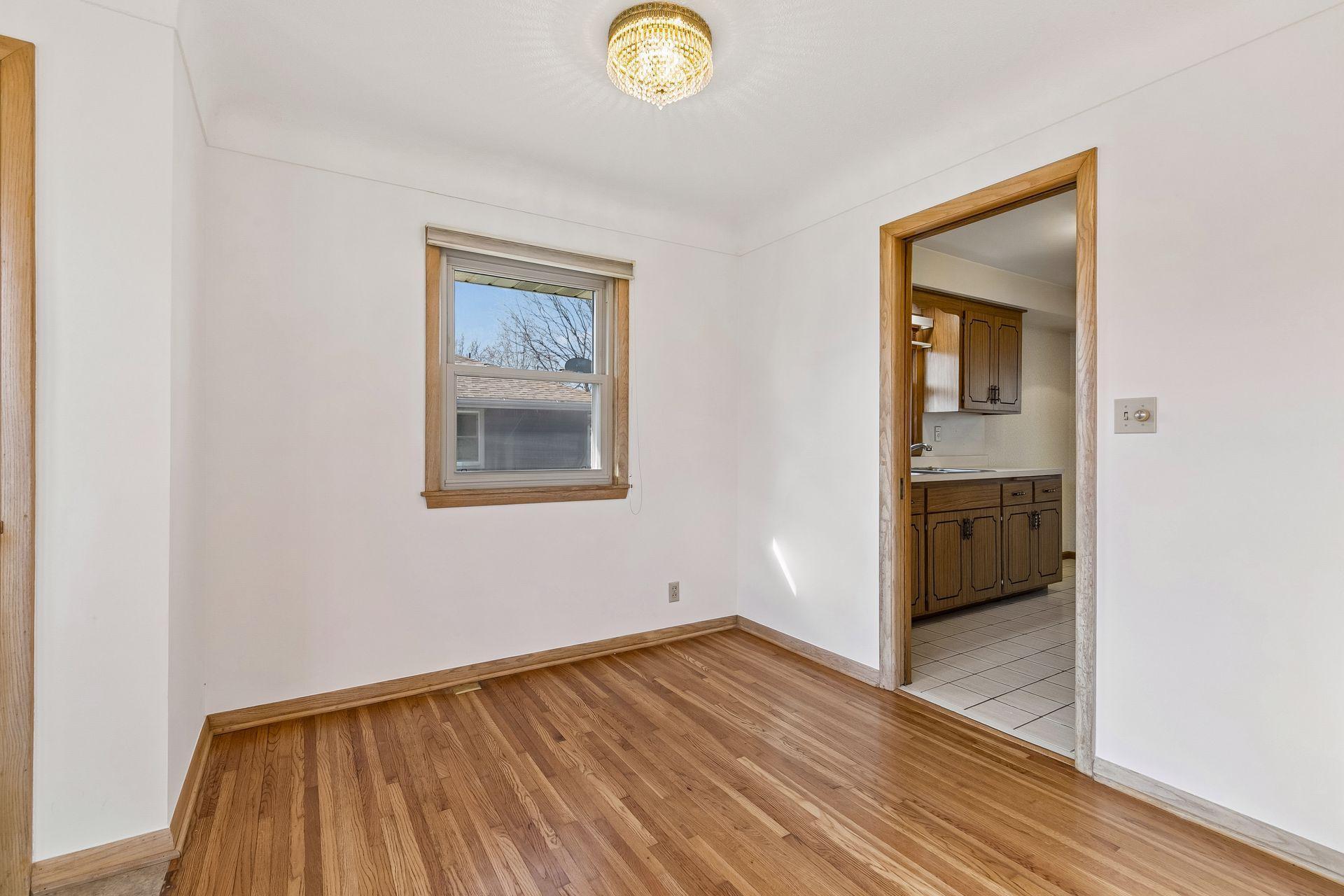 Designated dining space with convenient access to the kitchen, featuring hardwood flooring, overhead lighting and a beautiful window.