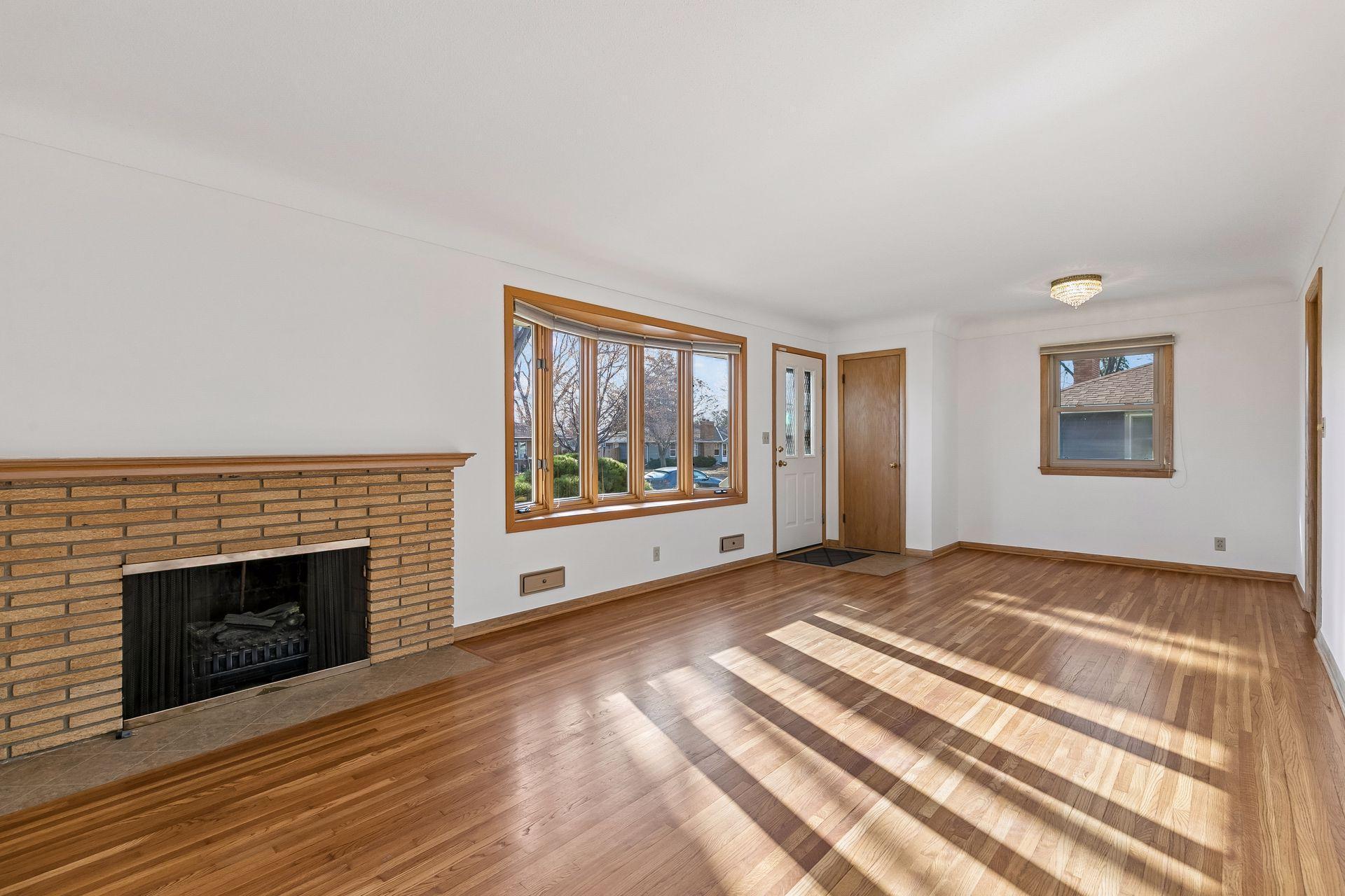 Step inside to a tiled entry with coat closet, opening to a charming living room with hardwood floors, a cove ceiling, bright bay window, and cozy wood burning fireplace.