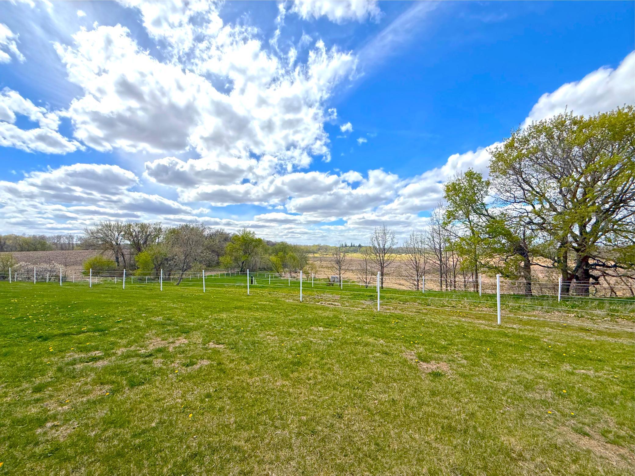 The property is surrounded by picturesque countryside, offering gently rolling land and wide-open views with fenced areas that provide functionality for livestock or horses.
