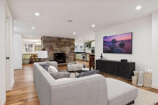 This stunning open-concept living area effortlessly combines style and comfort. Featuring a beautiful stone fireplace as the focal point, the room boasts elegant hardwood floors and recessed lighting.