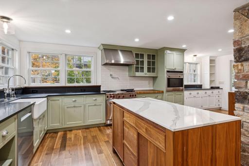 Elegant kitchen with high-end appliances, stone accents, and custom cabinetry. Features a spacious island, farmhouse sink, and large windows for abundant natural light. Perfect for entertaining.