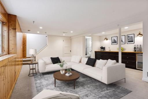 Spacious basement family room with a cozy fireplace, sleek bar area, and convenient half bath. Ideal for entertaining or relaxing in style.