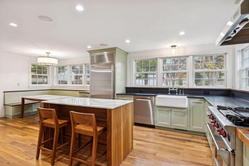 This stunning kitchen features expansive windows that flood the space with natural light, complemented by a cozy built-in sitting area perfect for casual dining or relaxing with a view.