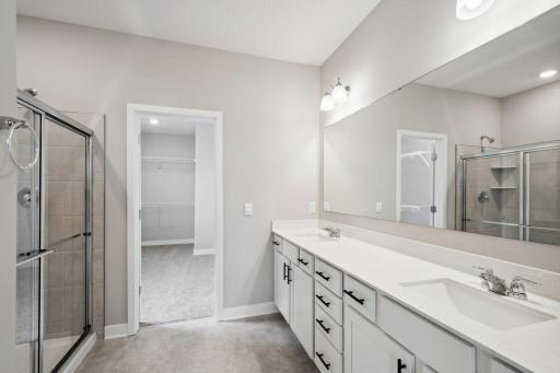 Primary ensuite bathroom with an exceptional walk-in closet. Spec home, colors and finishes will vary.