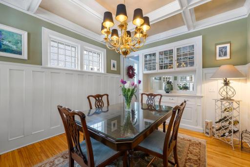 The elegant dining room has a built-in buffet, wainscoting, and box beamed ceiling