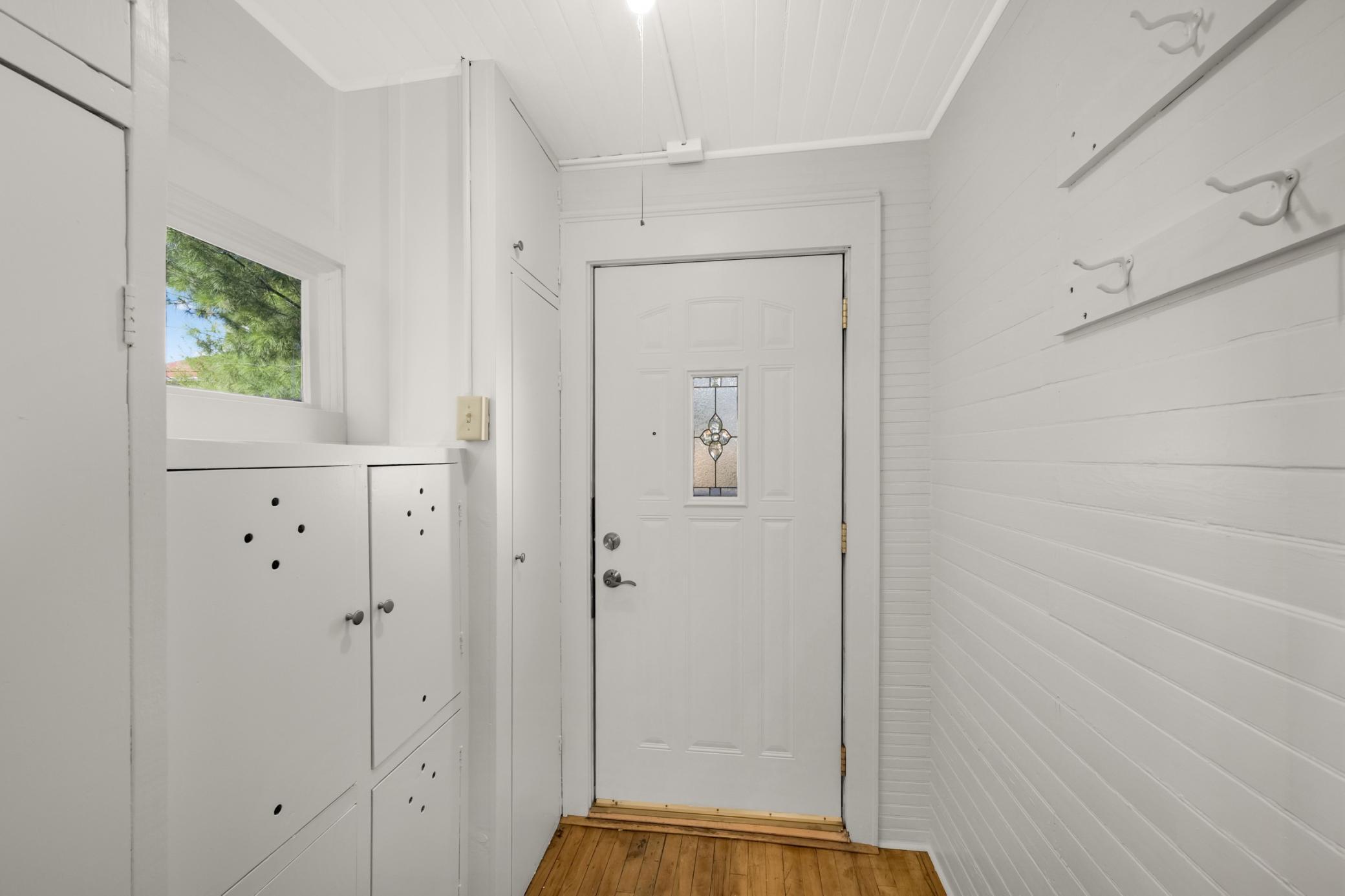 Versatile back door mudroom with storage cabinets for boots and jackets.