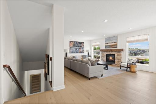 Spacious living room with cozy fireplace and large windows, seamlessly connected to the open main level *Photo of a Beckett model home - design options may vary.
