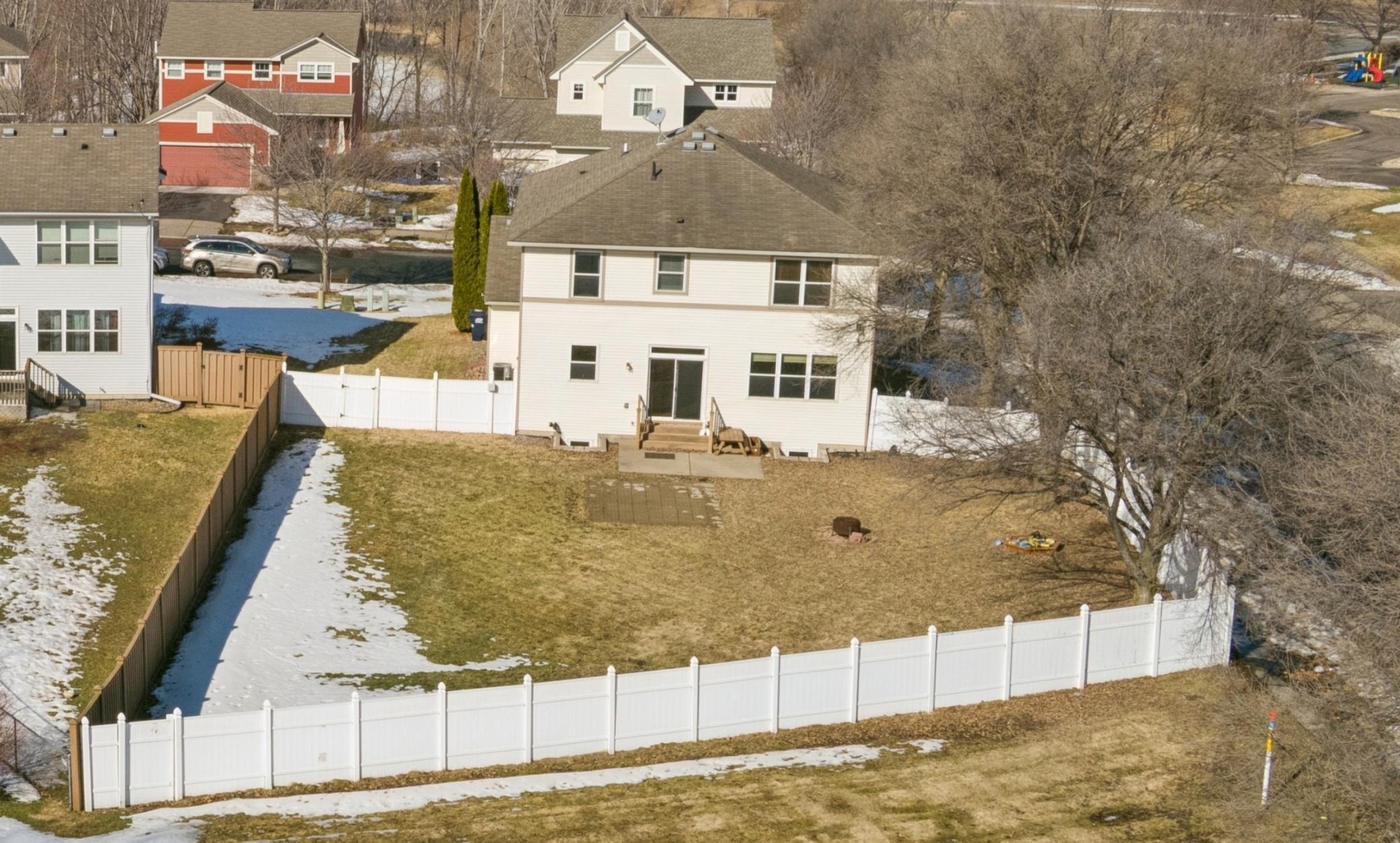 Flat backyard with two patios, irrigation system, and fully enclosed maintenance free privacy fence