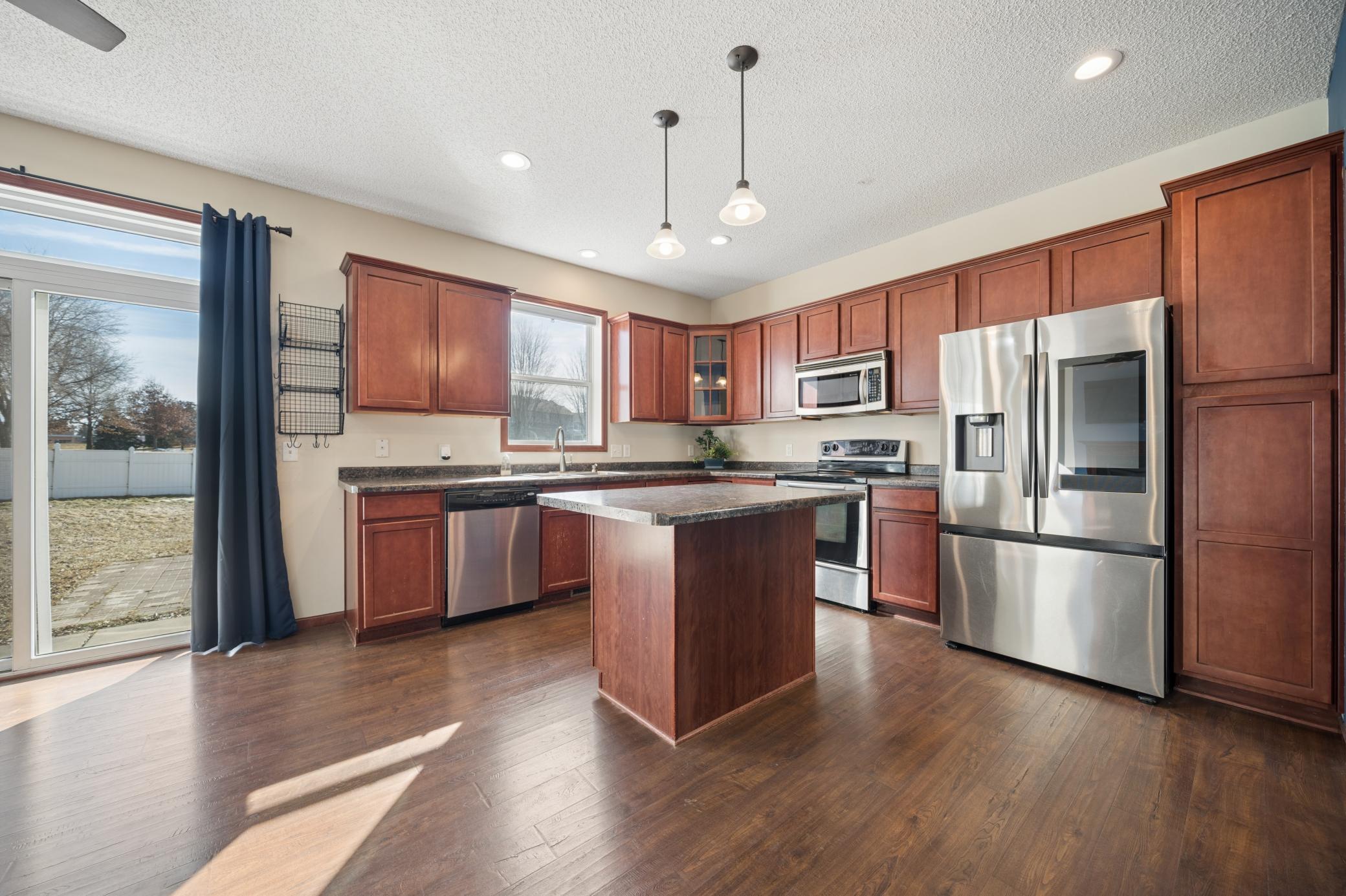 Cherry stained maple cabinets with stainless steel appliances and a center island with breakfast bar