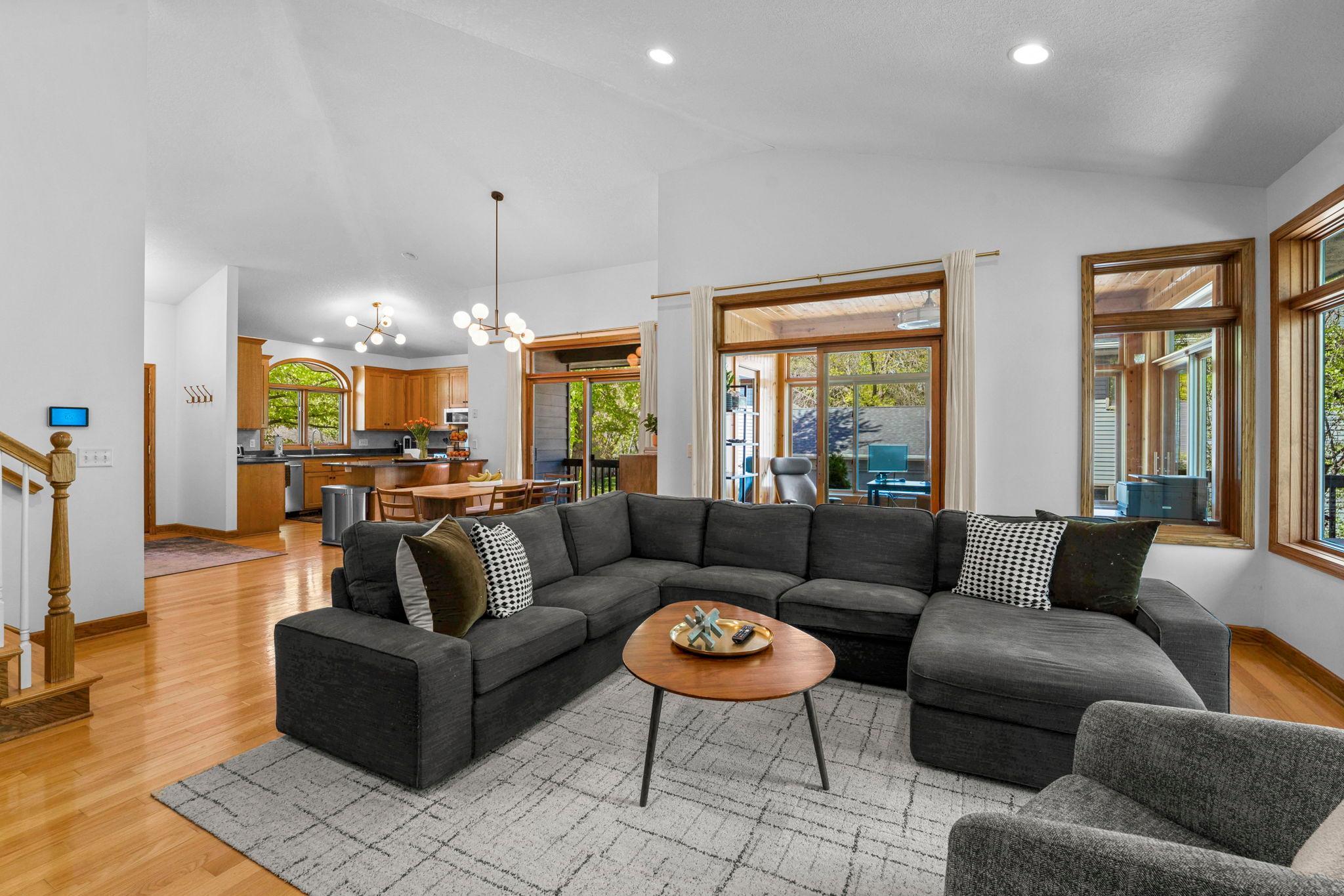 Home opens to a main living space featuring vaulted ceilings, natural woodwork, large windows and wooded view. The perfect mix of light filled, airy and warm!