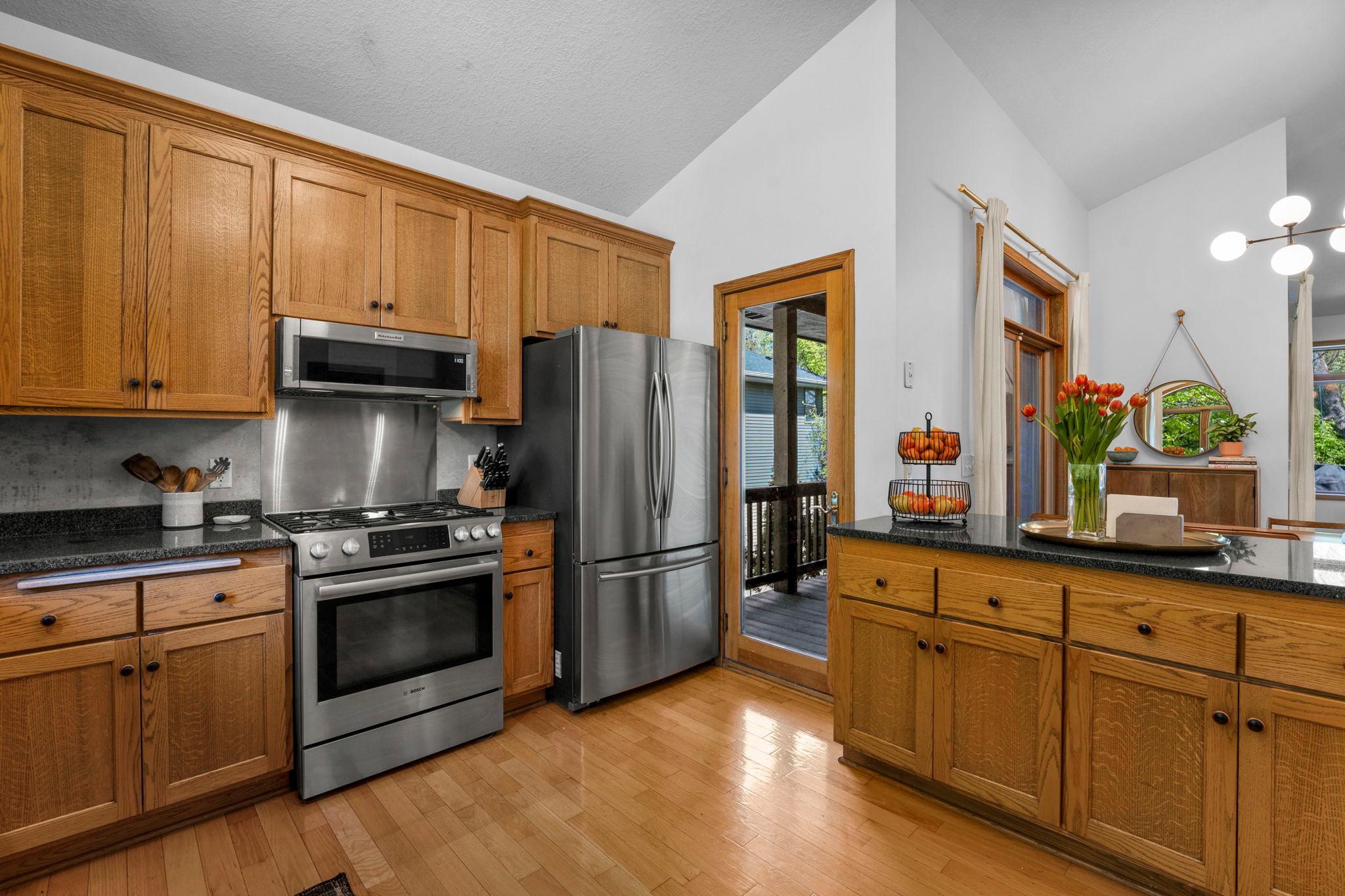 Large kitchen with island features tons of storage, quartz countertops, stainless appliances and balcony access.