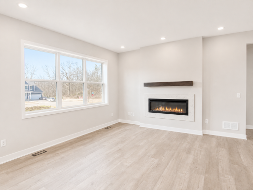 Spacious great room highlighted by a modern electric fireplace, expansive windows, and an open layout perfect for everyday living and entertaining.
