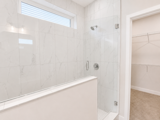 Spa-inspired walk-in shower featuring full-height tiled walls, a frameless glass enclosure, transom window, and designer finishes.