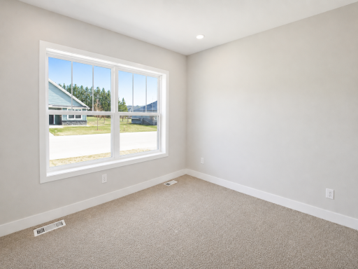 Comfortable main-level bedroom featuring a large window, abundant natural light, and a versatile layout ideal for guests or a home office.
