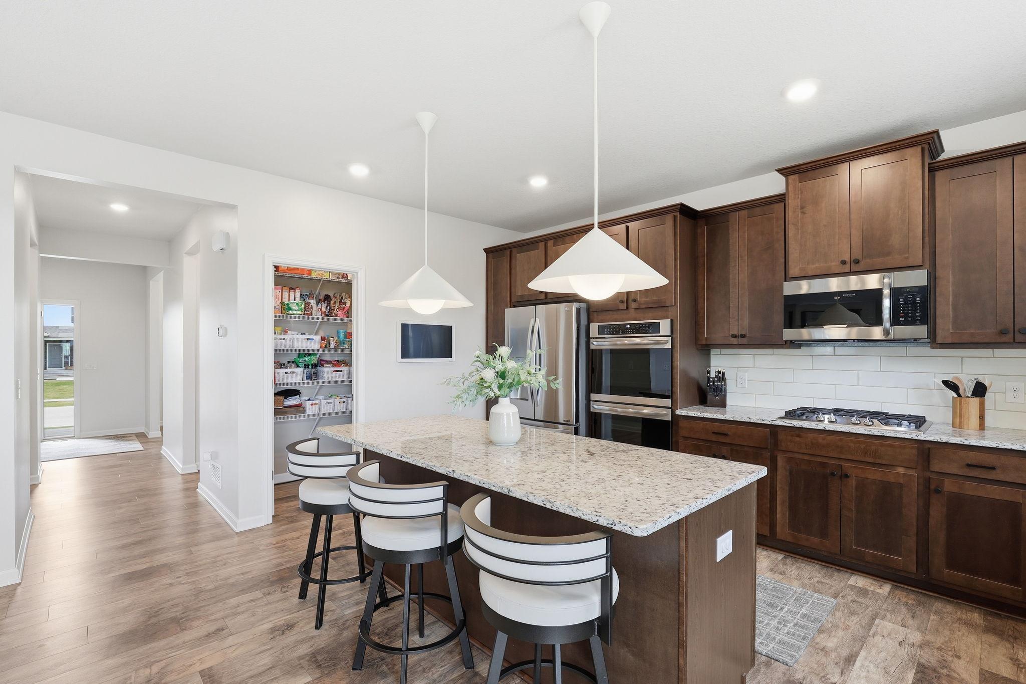 Other kitchen features; granite countertops, a spacious island, and a convenient pantry, combining style, function, and extra seating.
