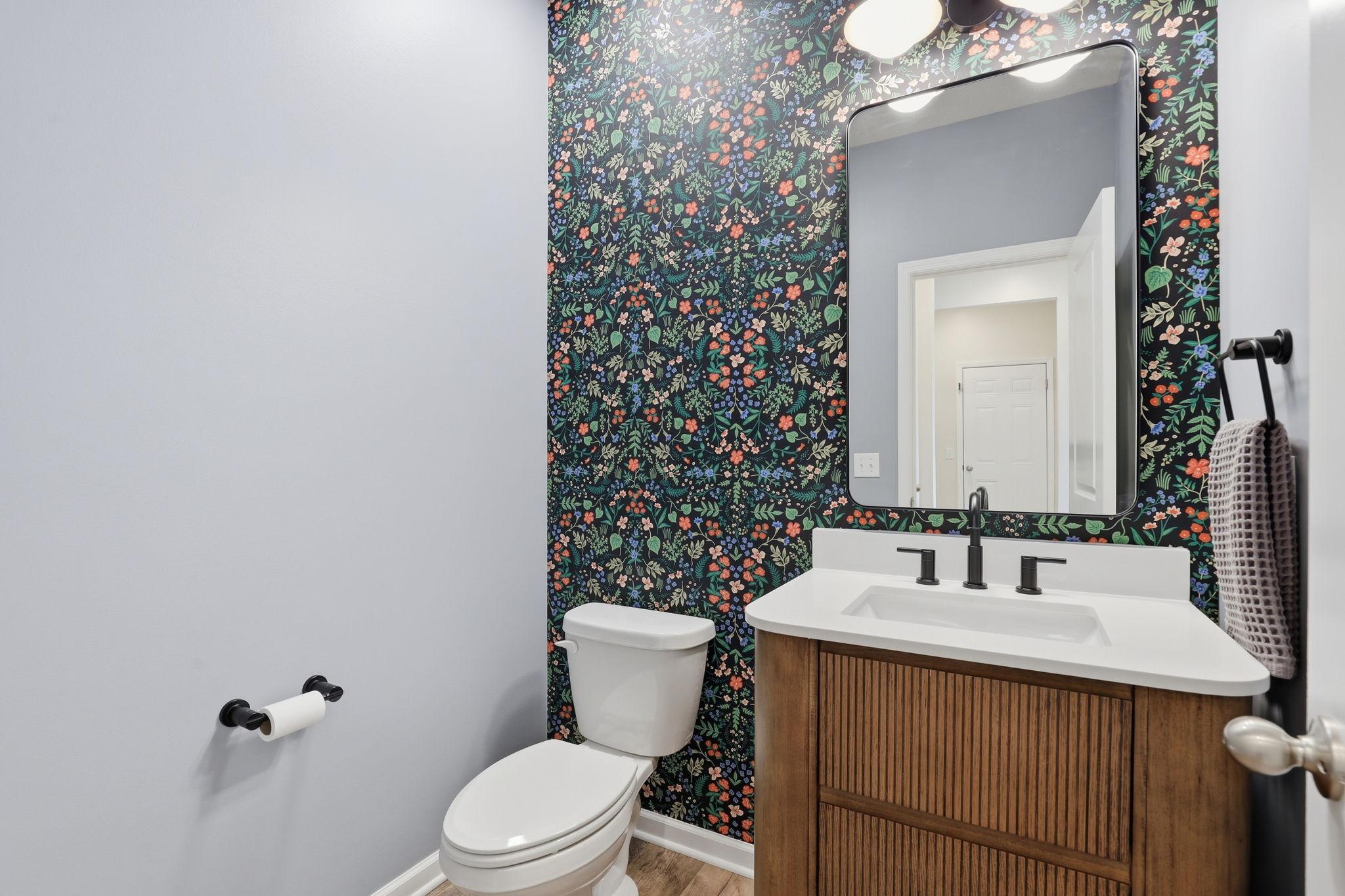 Main-level half bath updated with fresh paint, NEW wallpaper, and a NEW mirror for a modern refreshed look.
