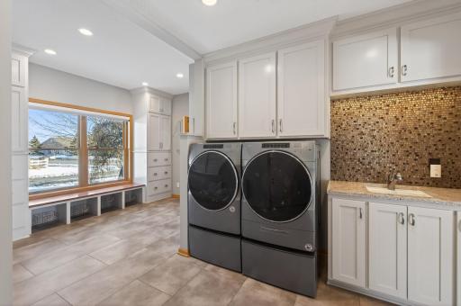 Dream laundry room with custom enameled cabinetry, flat-panel doors, under-cabinet lighting, and built-in laundry chute cabinet.