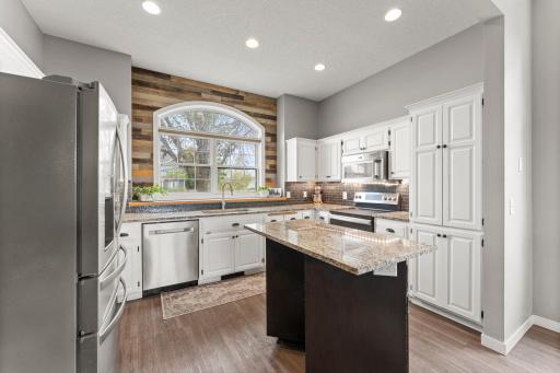 The kitchen brings plenty of personality and function with tall ceilings, abundant cabinetry, and tile backsplash.