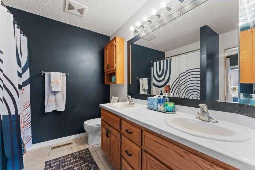 The bathroom is complete with tile flooring, dual vanity, and generous storage.