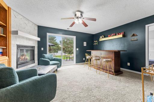 One level down from the main floor, the home shifts into its entertaining zone. The family room centers around a gas fireplace with tile surround and an entire wall of built-ins, creating an ideal setup for movie nights and displaying decor.