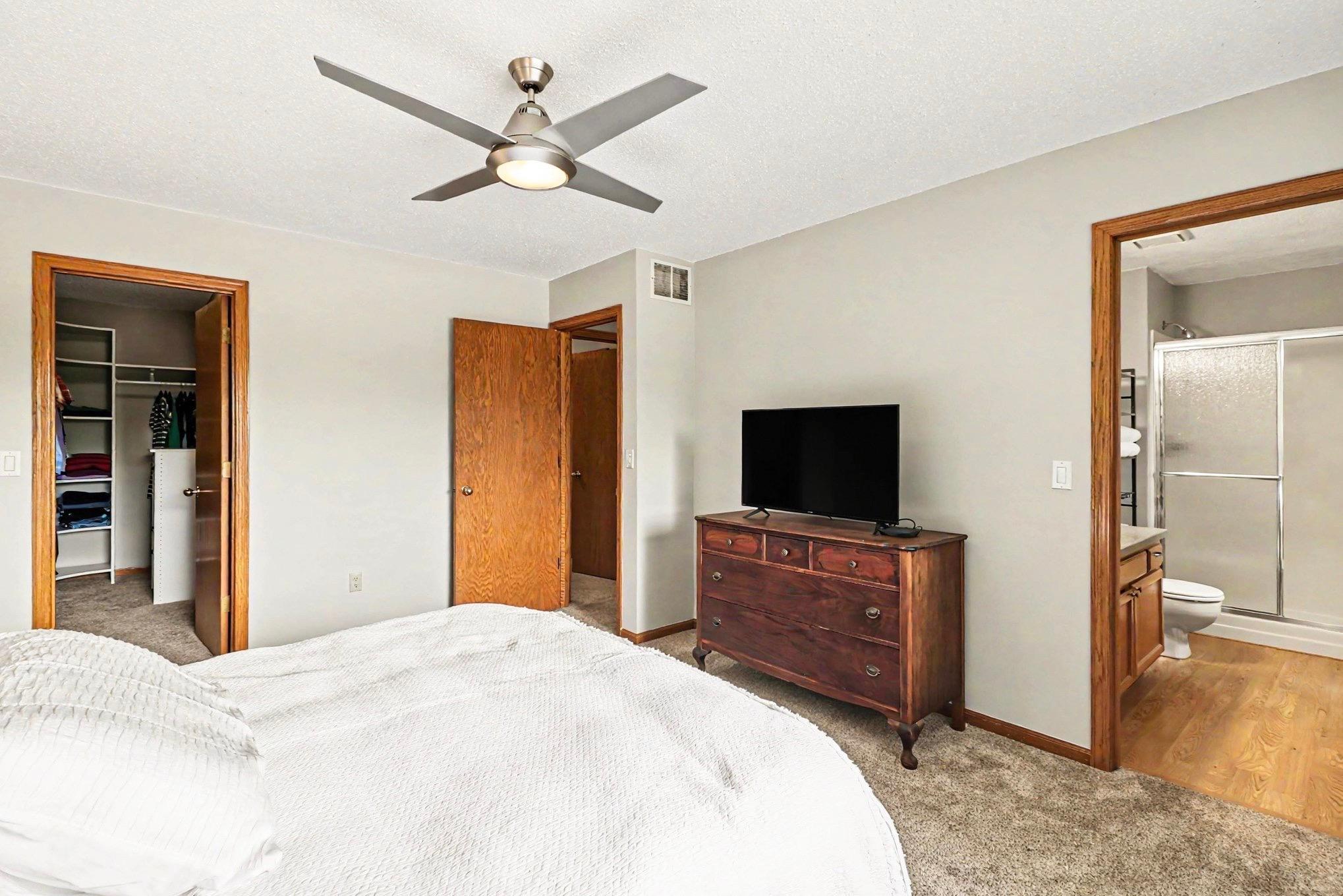large walk-in closet with built-in organizers and an ensuite bath